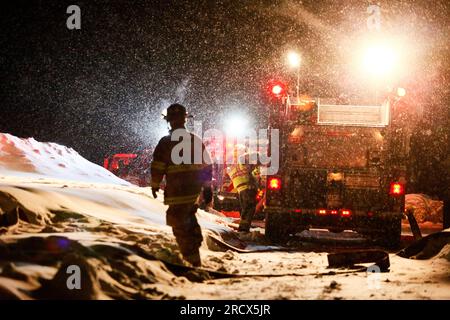 Firefighters prepare to fight a fire in a Vermont snowstorm at night. Stock Photo