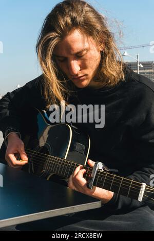 man with eyes close playing the guitar and studing music Stock Photo