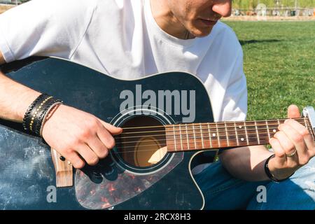 close up of a singer playing guitar in a garden during a sunny day Stock Photo
