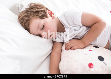 3 years toddler boy sleeping on bed with his favourite cushion Stock Photo