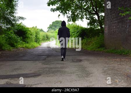 Images of people in hoodies walking through fields and under a narrow bridge. Stock Photo