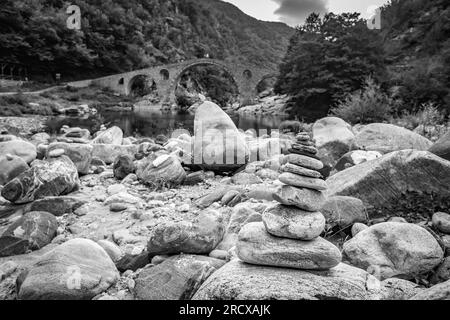 Zen small pile of stones, shallow focus perspective in front of Devil's bridge over river Arda, Southern Bulgaria. Black and white travel picture Stock Photo