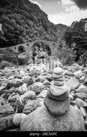 Zen small pile of stones, shallow focus perspective in front of Devil's bridge over river Arda, Southern Bulgaria. Black and white travel picture Stock Photo