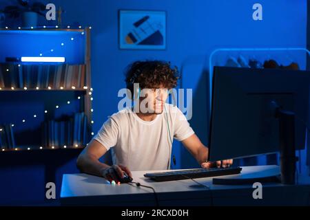 Arabic angry guy gamer playing video games on computer with neon light, looking with a scary face at monitor. Emotional video gaming. Stock Photo