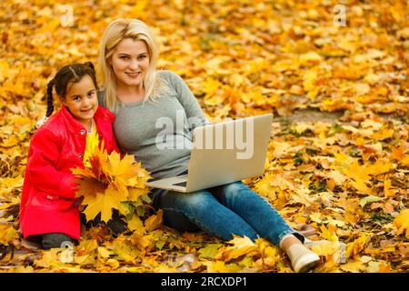 Happy mother and her tdaughter using laptop in the park. Stock Photo
