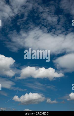 White puffy clouds set against a deep blue summer sky Stock Photo