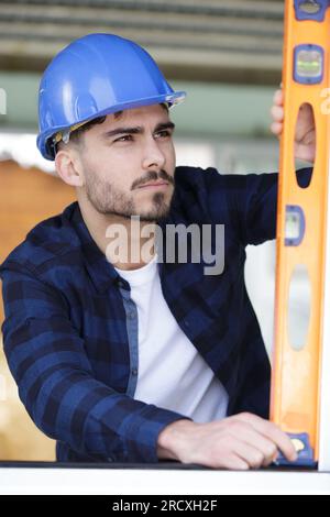 focused young builder using spirit level Stock Photo