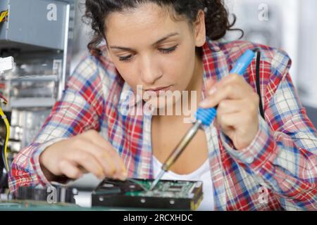 young female electronic engineer soldering computer motherboard in laboratory Stock Photo