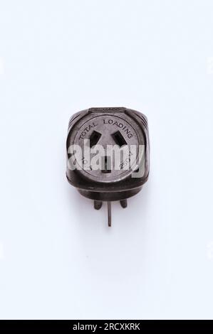 Art Deco Bakelite double adapter electrical plug showing one female face embossed with TOTAL LOADING and 10A and 250V and 3 pins on white paper Stock Photo