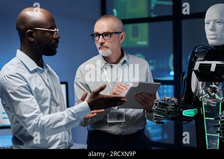 Multiethnic engineers using digital tablet to work with artificial intelligence in team in office Stock Photo