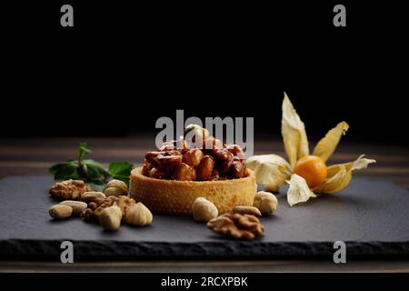 Dessert basket with nuts and caramel, on a black stone with mint Stock Photo