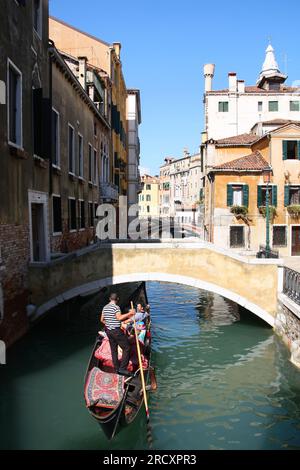 VENICE, ITALY - SEPTEMBER 16, 2009: Gondola tour in a canal of Venice, Italy. Venice Old Town is a UNESCO World Heritage Site. Stock Photo