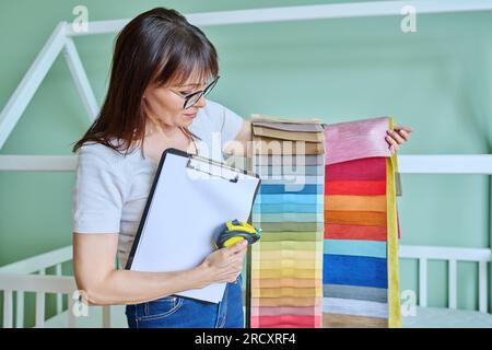 Woman interior designer with fabric tape measure clipboard in client room Stock Photo