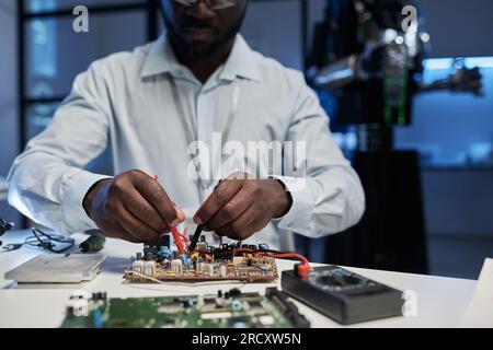 Close-up of African American engineer working with computer board at table in office Stock Photo