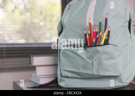 School supplies on wooden table in warm interior, school books on table, education concept. Stock Photo