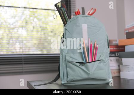 School supplies on wooden table in warm interior, school books on table, education concept. Stock Photo