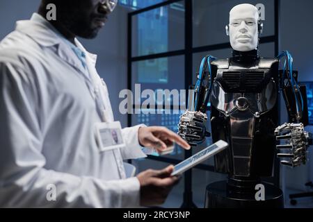 African American engineering in white coat using digital tablet to develop computer system of robot Stock Photo