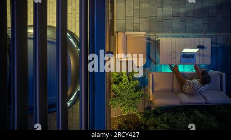 Men Working Remotely From His Backyard Using Laptop Computer Next to His Car Port. Modern Architecture Theme. Stock Photo