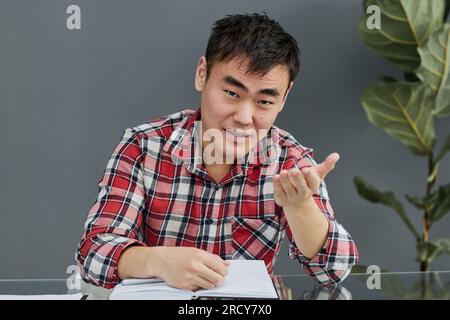 Young Asian man sitting at the table with his chin propped Stock Photo