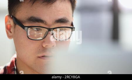man in shirt and glasses using laptop at work, investor pondering complex decision. Stock Photo