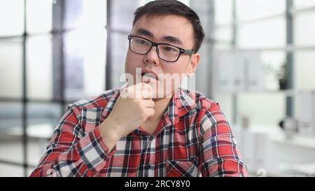 a young investor in casual clothes sits at a table and thinks about profit Stock Photo
