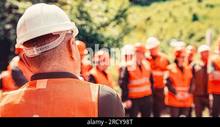 Helmet builder. Worker group wearing vest, safety. Building concept. Architector, engineers on constructing site. Builder man Stock Photo