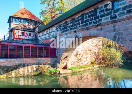 Arch bridge over the river in autumn . Old half-timbered houses on the banks of the Pegnitz river, Germany Stock Photo