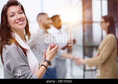 a team of four with a woman leader in the foreground stands in a modern office Stock Photo