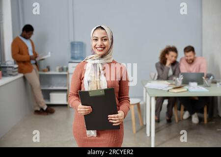 Young successful chief executive office or director of business company holding folder with documents and looking at camera in office Stock Photo