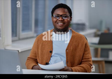 Happy young African American male chief executive officer or analyst with paper in hands looking at camera while working with documents Stock Photo