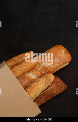 Bakery products in a paper bag. Sale of pastries, fresh bread. Baguettes, sesame buns and a loaf Stock Photo