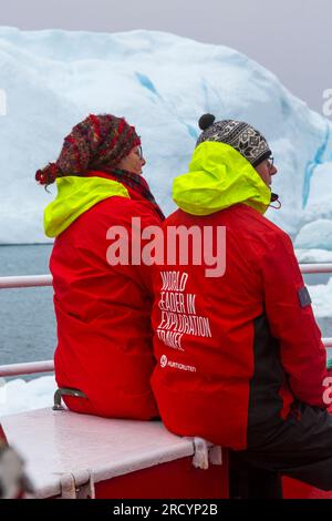 World Leader in Exploration Travel on back of Hurtigruten red jacket clothing of tourists at Ilimanaq, Disko Bay, Greenland in July Stock Photo