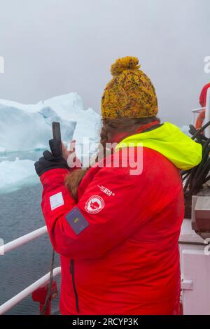 Tourist wearing red jacket on board boat at Ilimanaq, Disko Bay, Greenland in July Stock Photo