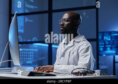 African American engineer concentrating on his work on computer while sitting at his workplace in the lab Stock Photo