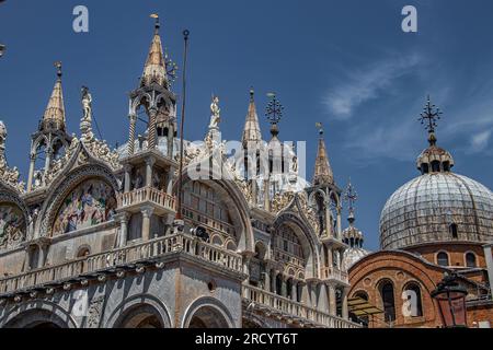 Details of St Mark's Basilica or the Basilica di San Marco in Italian, golden mosaics, intricate carvings, and statues adorn the roof of St. Mark's Stock Photo