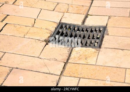 Iron cast manholes in a old stone paving in a pedestrian urban zone Stock Photo