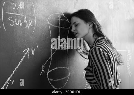 Stressed female Math teacher near blackboard in classroom Stock Photo