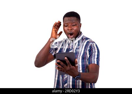 portrait of a handsome young man surprised standing against white background using a digital tablet. Stock Photo