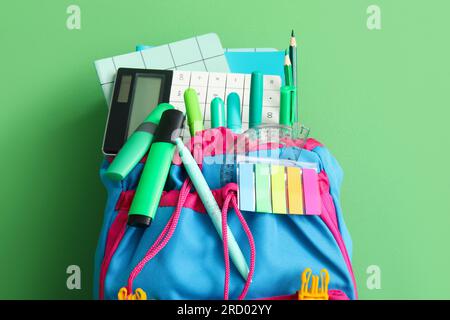 School backpack with different stationery on green background Stock Photo