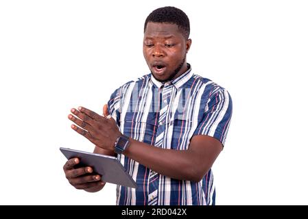portrait of a handsome young man surprised standing against white background using a digital tablet. Stock Photo