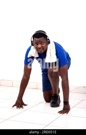young man with towel around his neck playing sport in a gym and listening to music using headphones. Stock Photo