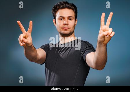 Young brunette man showing victory handsign Stock Photo