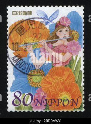 RUSSIA KALININGRAD, 22 APRIL 2016: stamp printed by Japan, shows  girl in dress made of flowers playing on flute, circa 2013 Stock Photo