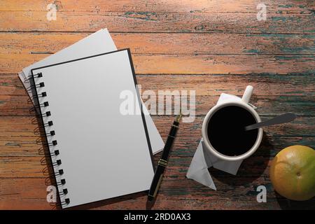 Notebook with blank sheet of paper, pen and cup of coffee on wooden background. 3D render illustration. Stock Photo