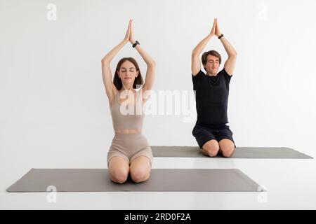 Serious calm millennial european couple in sportswear sit on floor practicing yoga, breathing exercises Stock Photo