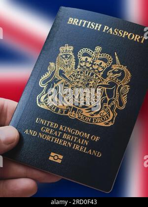 Hand holding a British Passport in front of the Union Jack.  Travel document for Untied Kingdom and Northern Ireland Stock Photo