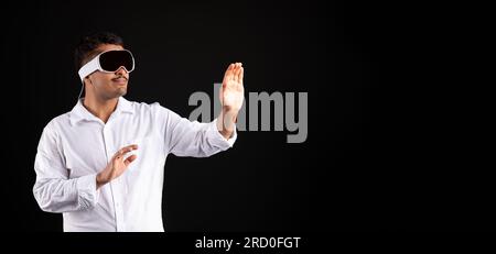Young latin man using visual pro VR glasses gesturing with hands, interacting with virtual reality, panorama, free space Stock Photo