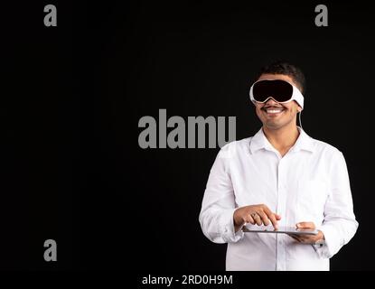 Male CGI artist drawing using graphics tablet and vision pro vr glasses on black background, free space Stock Photo