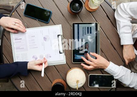 Hands of businesswomen using financial service application on tablet computer, view from above Stock Photo