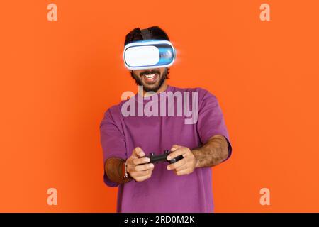 Smiling eastern young guy using VR glasses and joystick Stock Photo